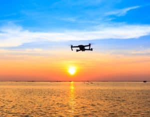 Drone flying over the ocean with sunset