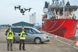 Two Men Flying Drone by Ship
