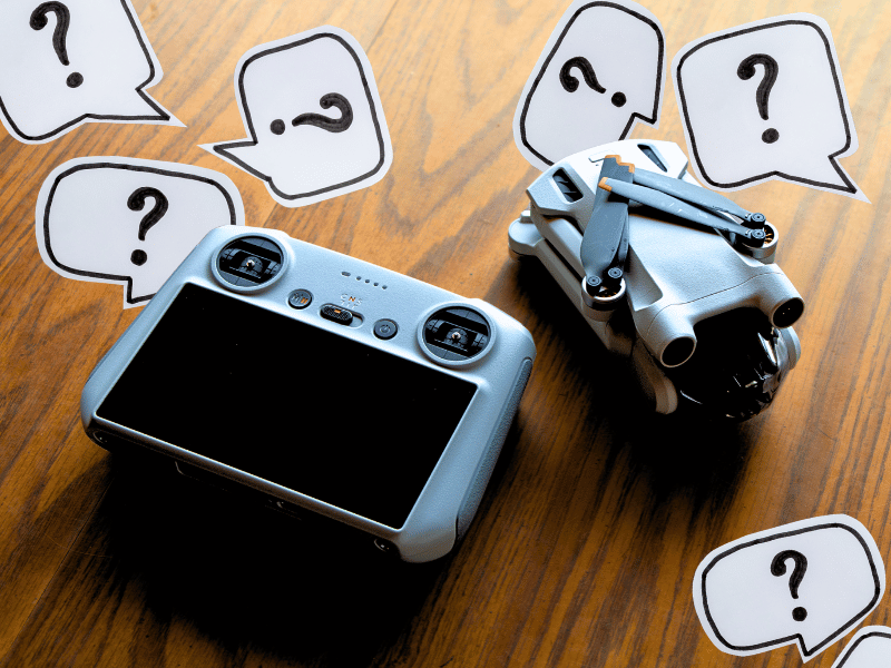Drone and remote on a table surrounded by question marks - Questions to Ask When Buying Drone Insurance