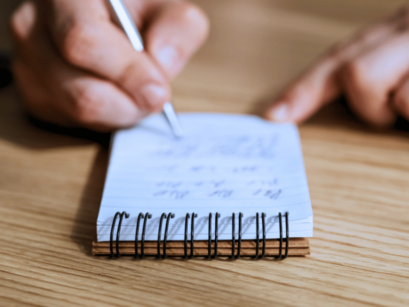 Person writing a list on a notepad