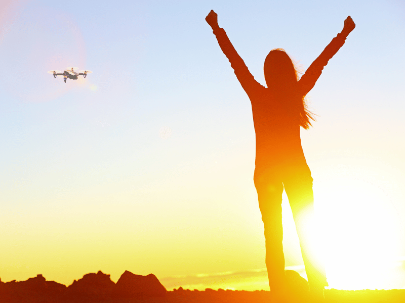 Person celebrating in front of a bright sun on the horizon - Best Drone Insurance 2026