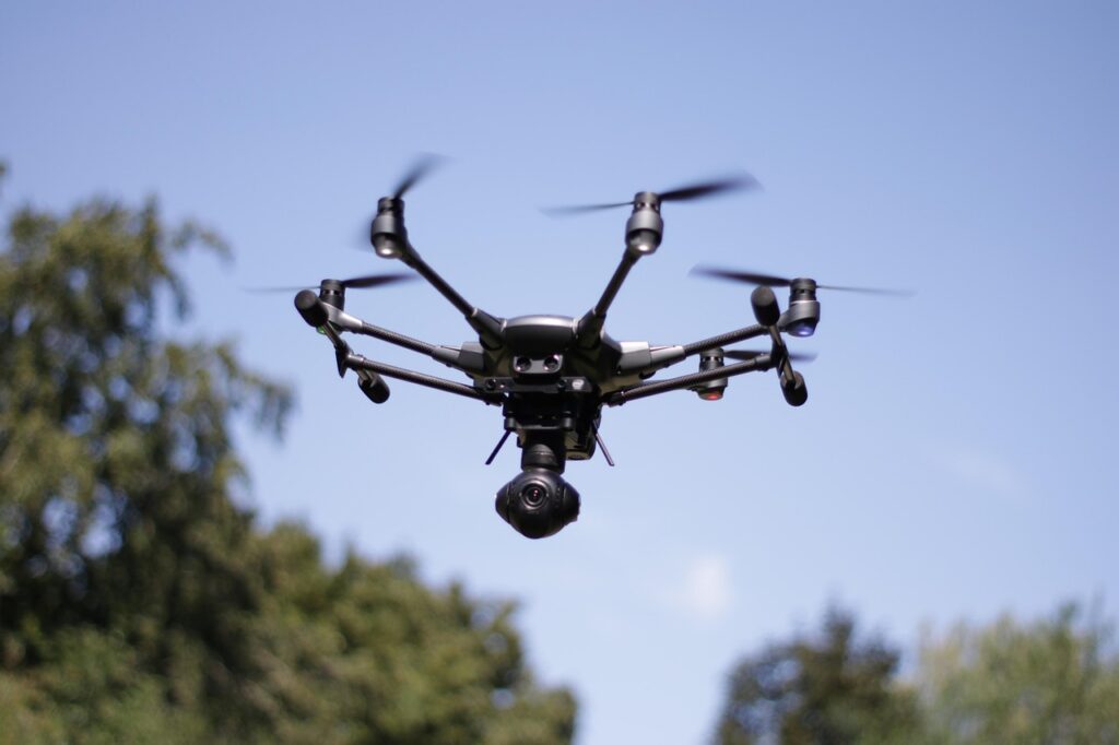 Drone flying above trees with blue sky in background