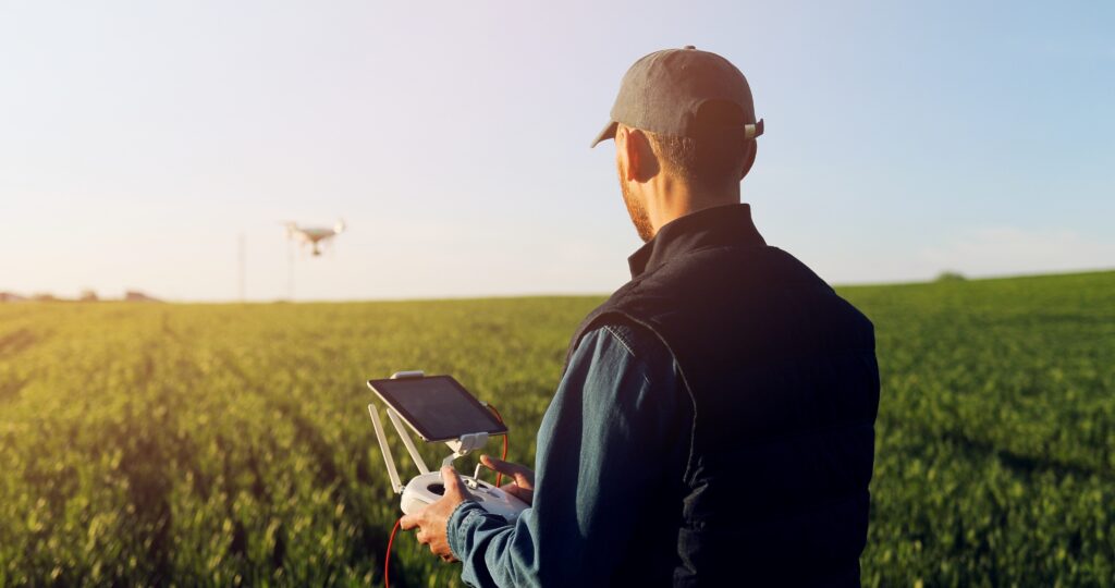 Commercial drone pilot flying UAV over farmland, illustrating lawful flying, operational oversight and commercial drone insurance.