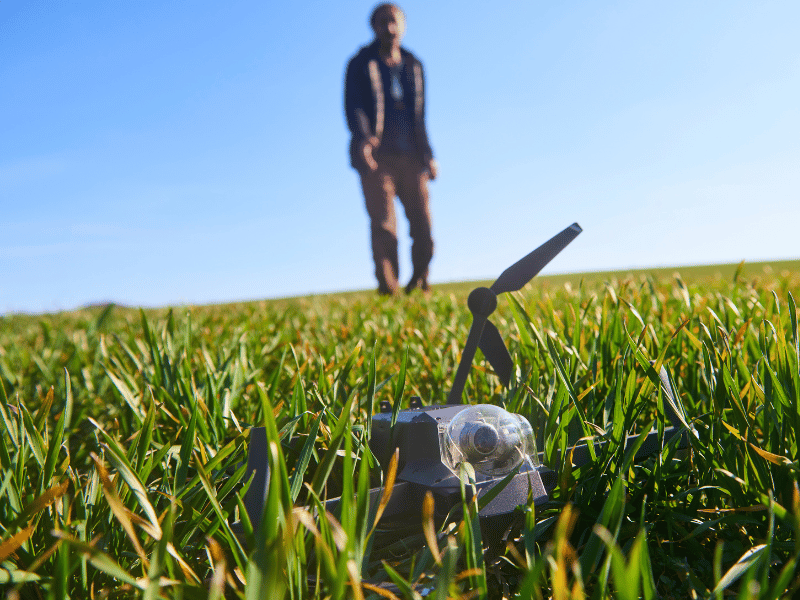 Person checking on a drone that has crashed in a field