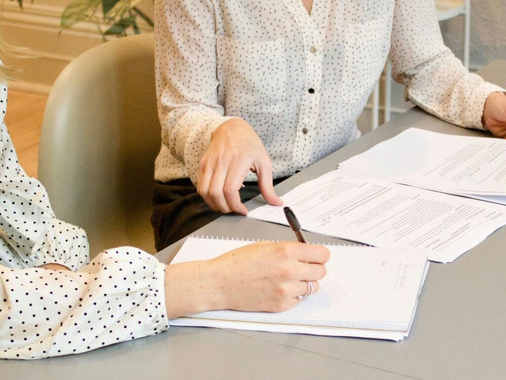 Two people at a table with paperwork, demonstrating compliance