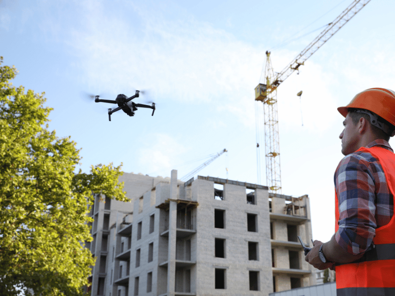 Drone operator flying a drone near a construction site for inspection work